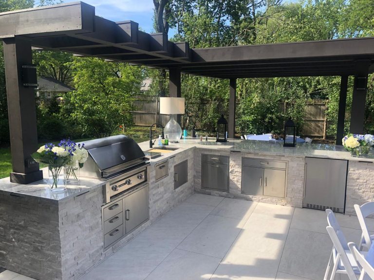 Large L-shaped outdoor kitchen with granite bar seating under a modern pergola