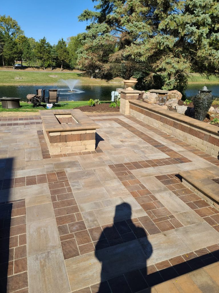 Paver patio and fire pit beside a backyard pond and water feature in DuPage County, IL